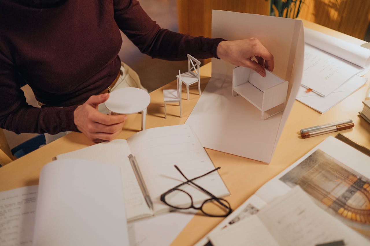 Architect working on miniature furniture models in a creative workspace. Focus on handmade design process.